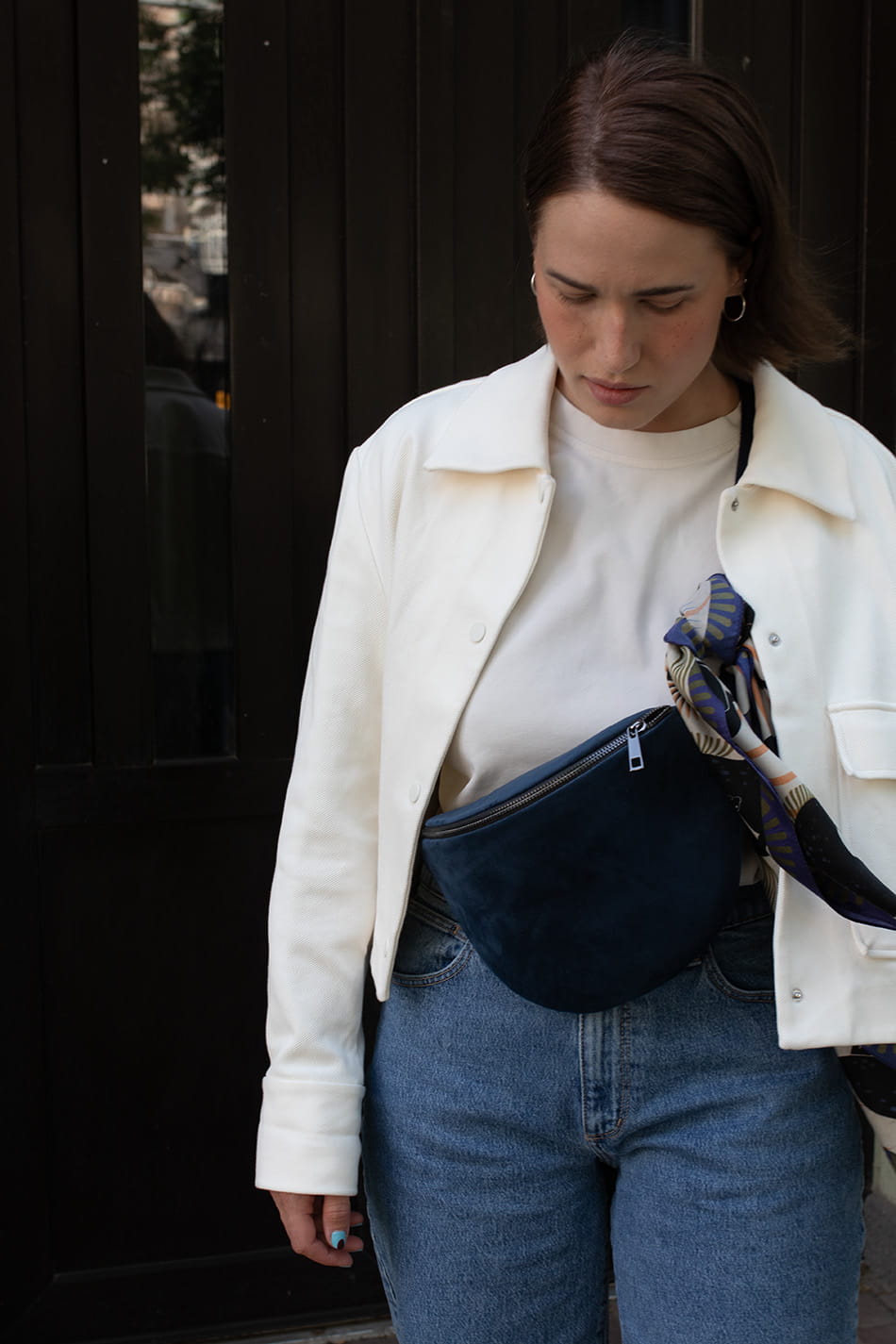 Nerka Black Iris z ciemnogranatowego aksamitu. Metalowy suwak i okucia pasków - stare złoto.  Prezentowana w rozmiarze midi, z paskiem z czarnej taśmy 25mm. Noszona na skos, przez ramię. Ozdobiona kolorową apaszką.