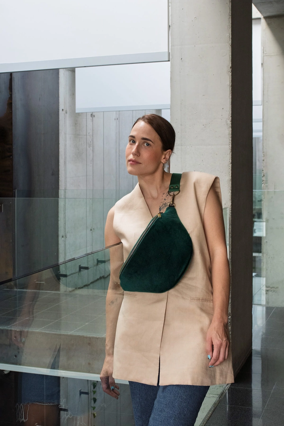 Aksamitna nerka Ponderosa Green, w odcieniu ciemnej zieleni. Zapięcie na metalowy suwak i okucia pasków w starym złocie. Modelka prezentuje rozmiar maxi na pasku z ciemnozielonej taśmy 40mm.