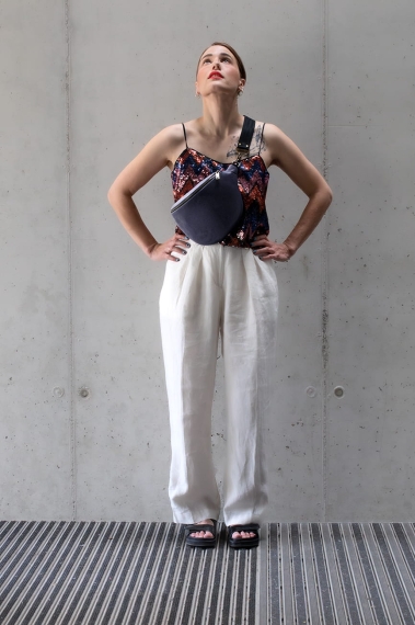 Lawendowa nerka aksamitna Heron. Trwały materiał. Okucia w starym złocie. Modelka prezentuje rozmiar midi, na pasku z czarnej taśmy 40mm.